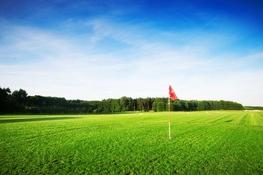 Golf field with green grass and red flag.