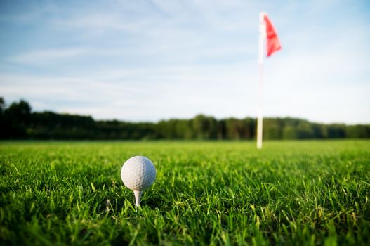 Golf field with green grass and red flag.