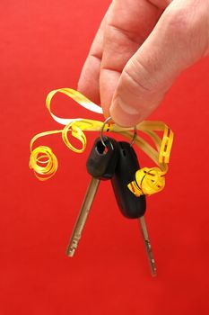 Hand holding car keys gift on red background