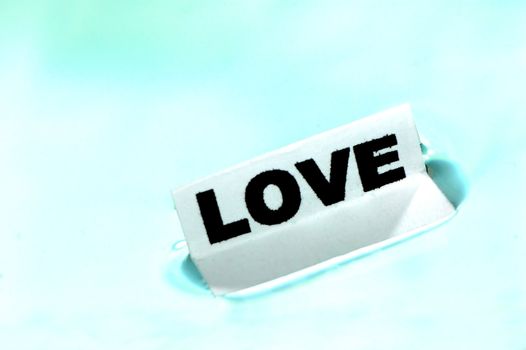 Card floating on water surface with printed word: LOVE