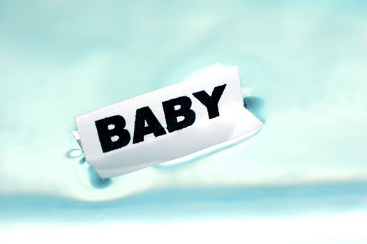 Card floating on water surface with printed word: BABY