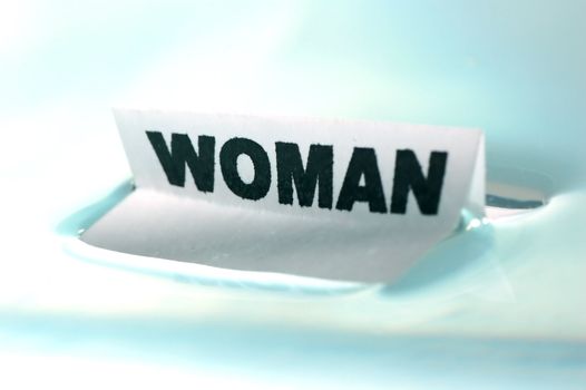 Card floating on water surface with printed word: WOMAN