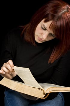 Girl turning a page in a dictionary.

Shot in studio.