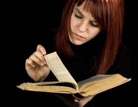 A beautiful redhead girl studying from a book.

Studio shot.