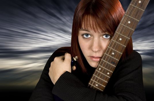 Depressed redhead girl protecting her guitar with a dramatic background.