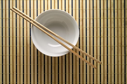 Bowl and chopsticks on bamboo mat