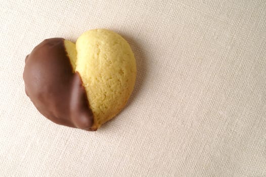 Heart shaped chocolate dipped cookie over linen