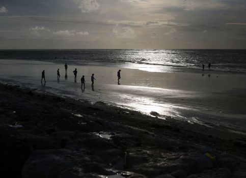 Silhouettes of people on an evening beach. Bali. Indonesia