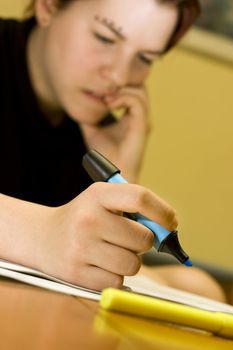 A pensive redhead student girl marking notes with a blue marker and biting her nails .

Lit with three strobes, two ambient ones and one umbrelled from the left.