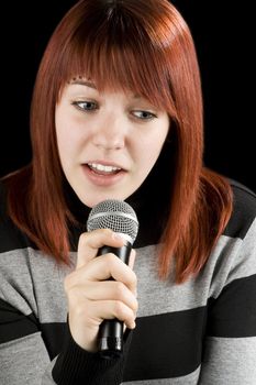 Girl holding a microphone singing karaoke. Redhead.

Studio shot.
