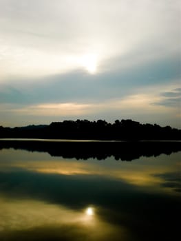 Beautiful reflection of the sky and clouds on the water with the sun shinning.