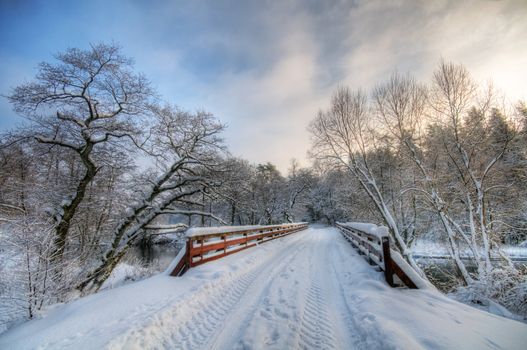 Bridge in winter forest during sunset, lots of snow