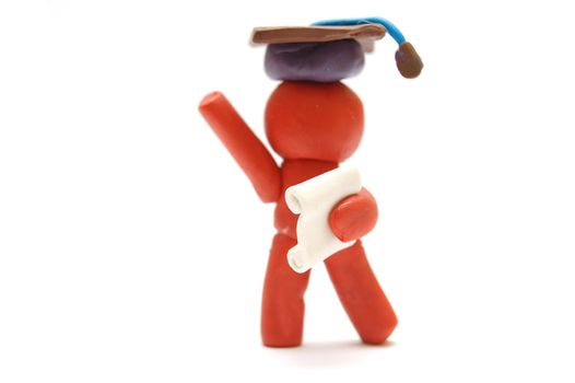 Plasticine figure celebrating graduation with certificate and student hat