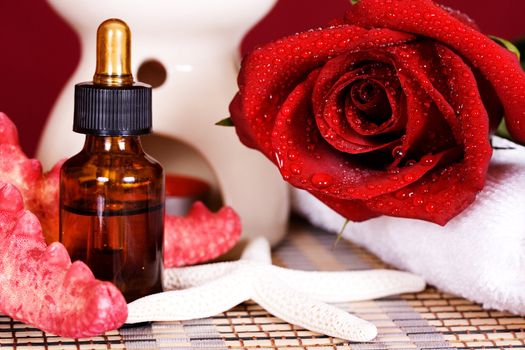 Essential oil and red rose a burning candle
