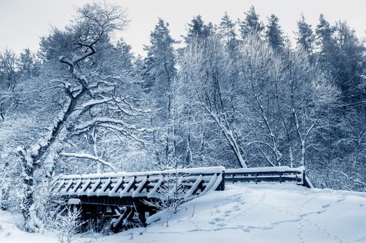 Bridge in winter forest during sunset, lots of snow