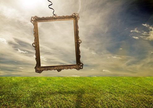 Empty retro frame hanging on poor grassy land. Conceptual.