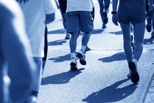 Running fast in marathon, legs close up. Sport, competition, energy.