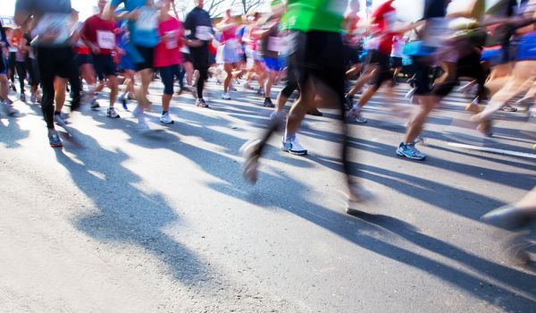 Running fast in marathon, legs close up. Sport, competition, energy.
