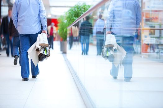 People in rush in a modern shopping mall. Close up and reflection of a man walking