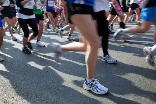 Running fast in marathon, legs close up. Sport, competition, energy.