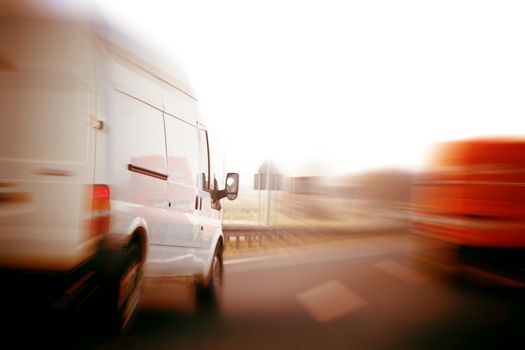 Transportation, logistics concept. Delivery vans, trucks on a freeway, speed motion blur.