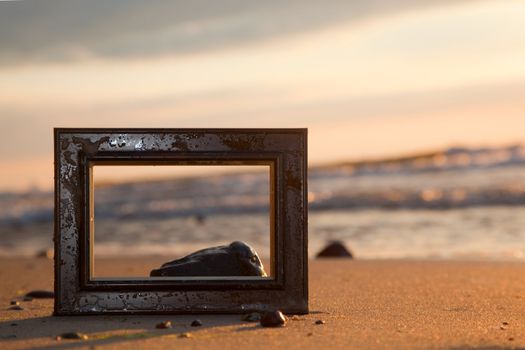 Frame on the beach at sunset. Conceptual, memories from holidays.