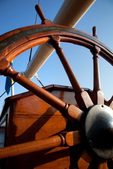 Old, wooden helm on blue sky. Navigation