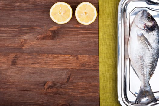 Dorado fish on a wooden surface with slices of lemon