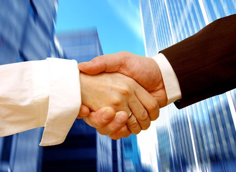 Business handshake on abstract skyscrapers background