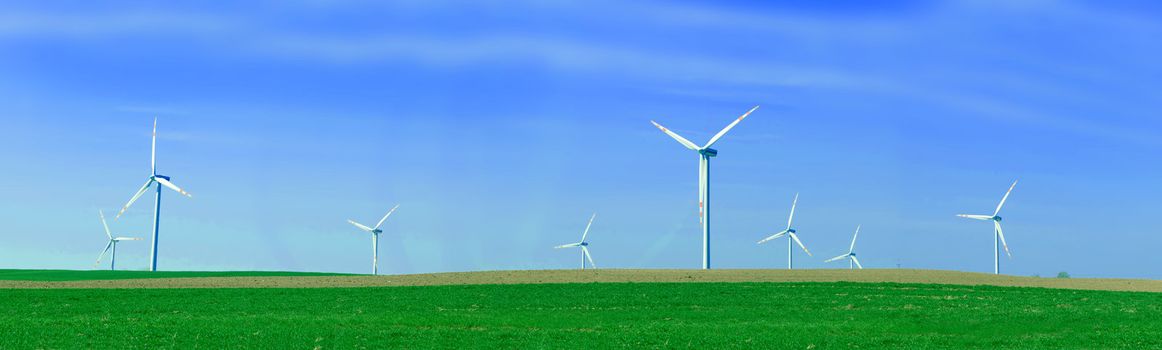 Panorama of the wind turbnes on a summer field