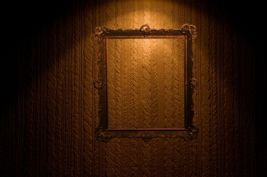 Old ornamented frame on retro grunge wall with mysterious lighting