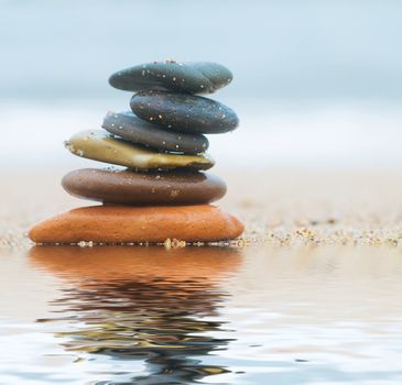 Stack of beach stones on sand. Ocean in the background
