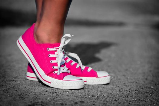 Pink sneakers on girl, young woman legs, outdoors in black and white