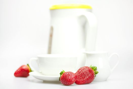white cup, milk jug, teapot and strawberries isolated on white