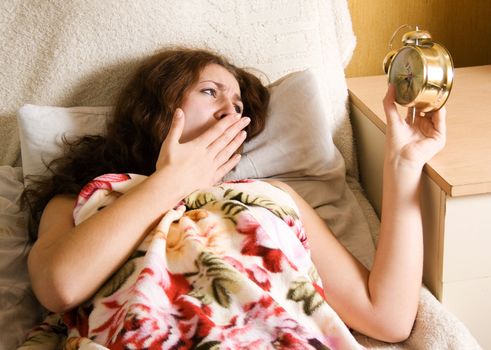 Surprised woman holding alarm clock