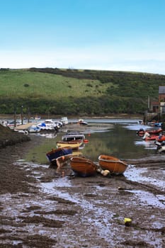 An inlet at low tide at Salcombe harbour in devon, england, with wooden boats to the foreground.