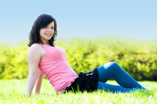 Young happy smiling girl lying on grass