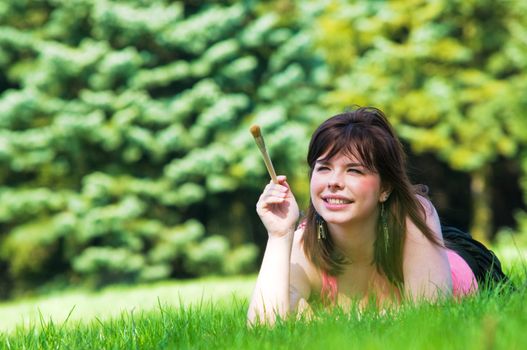 Painting the world. Smiling girl on grass with a paintbrush