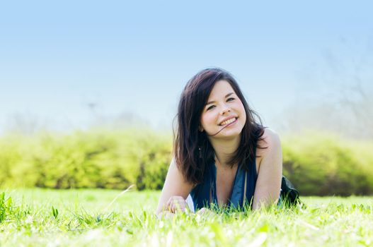 Young happy smiling girl lying on grass