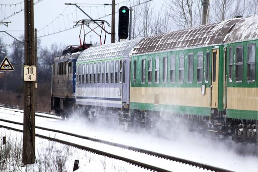 Passenger train passes the snowy line during wintertime in Poland
