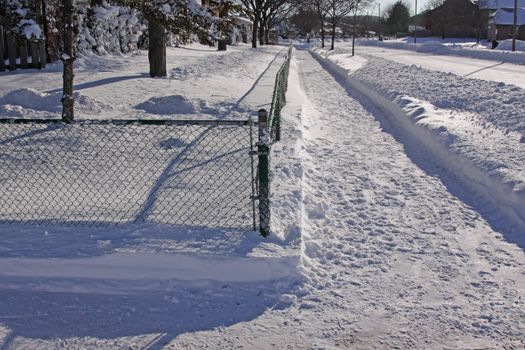 Snow fall in the suburbs, featuring a cleared side walk corner.