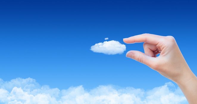 Woman hand taking cloud against blue sky with clouds. Concept image on cloud computing and eco theme with copy space. 