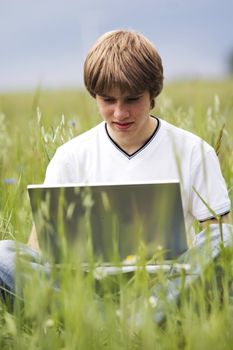 Boy using notebook outdoor on the field