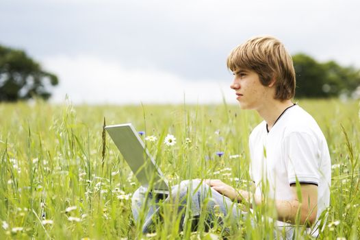 Boy using notebook outdoor on the field