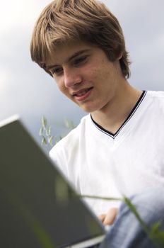 Boy using notebook outdoor on the field