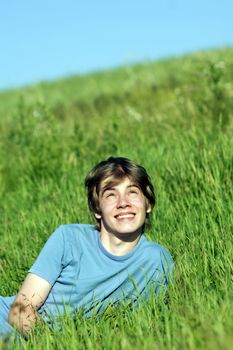 Young happy boy lying on the grass