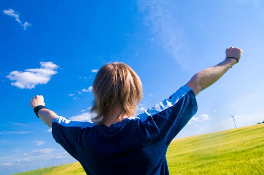 Happy man with arms up on summer landscape