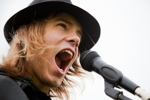 Young man in hat sings to microphone