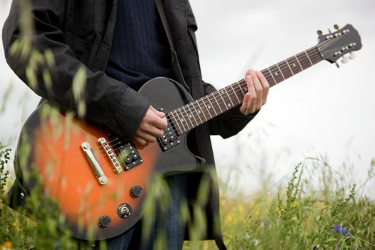 Close up of a man playing guitar outdoors