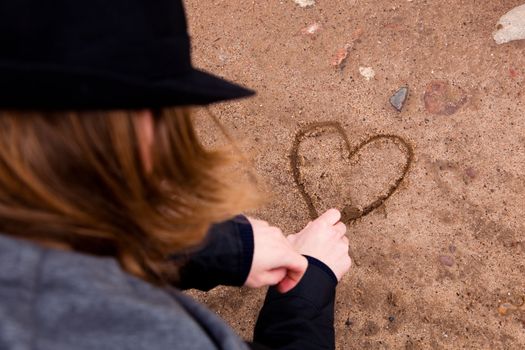 Young man drawing a heart shape on ground